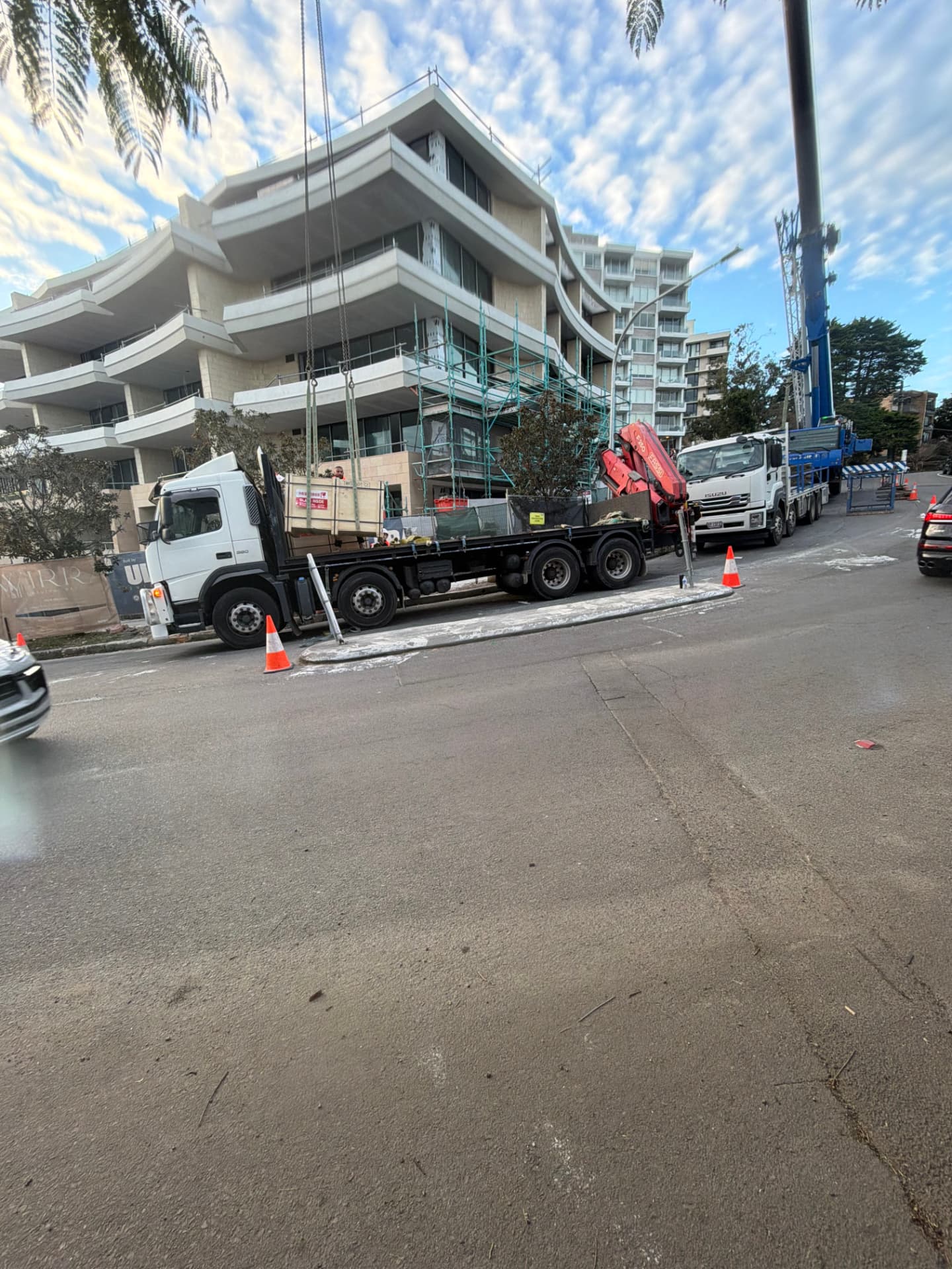 Crane truck loaded with timber glass crates parked on a Sydney street beside an apartment build
